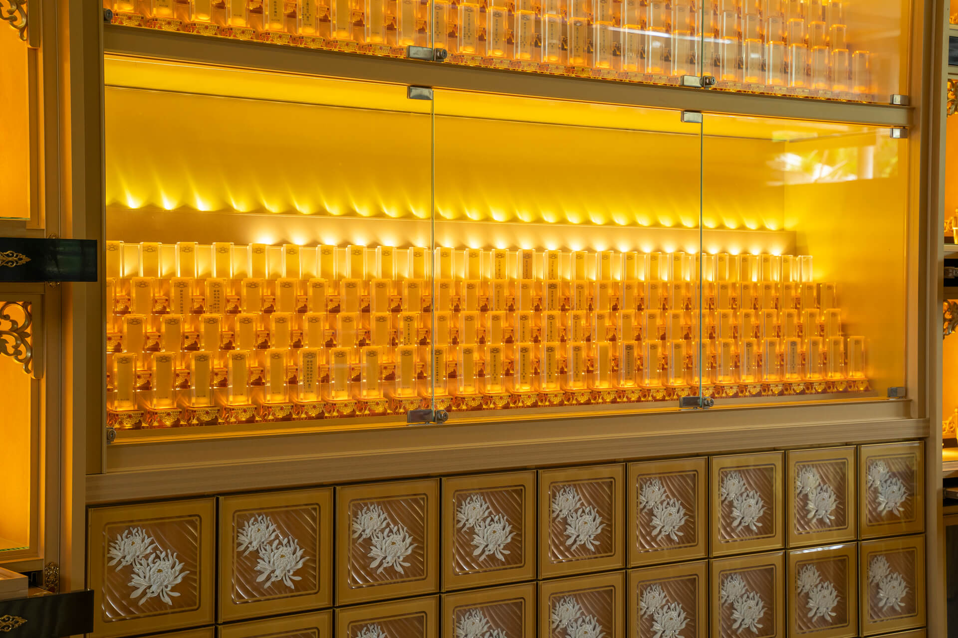 神主牌位柜，灯光下整排牌位｜Rows of lit ancestral tablets in a glass display cabinet